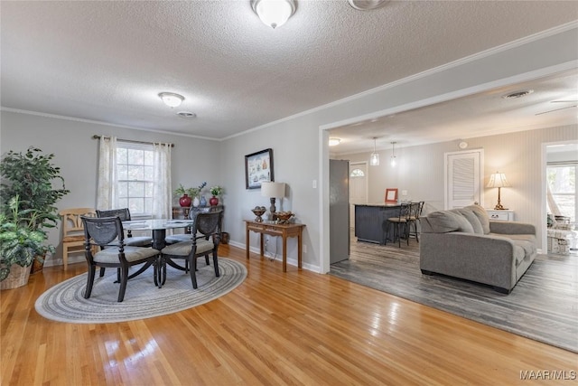 dining area with hardwood / wood-style floors, a textured ceiling, plenty of natural light, and crown molding