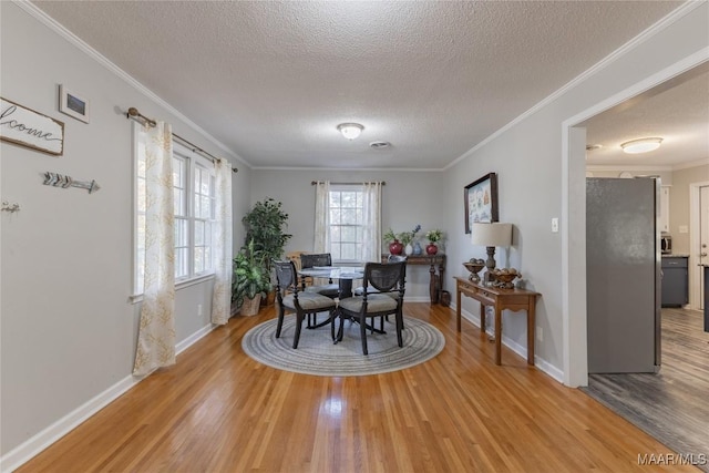 dining space featuring crown molding, wood-type flooring, and a textured ceiling