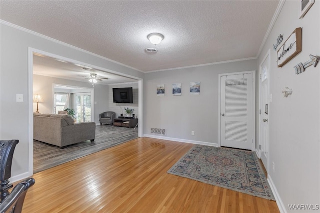 foyer entrance with ceiling fan, ornamental molding, a textured ceiling, and hardwood / wood-style flooring