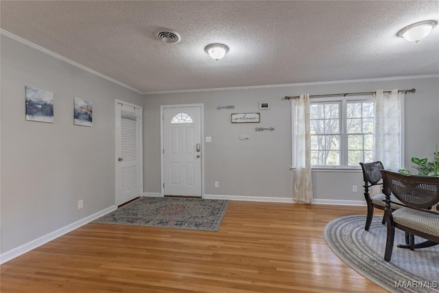 entrance foyer featuring crown molding, light hardwood / wood-style flooring, and a textured ceiling