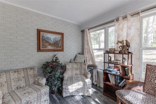 sitting room with dark wood-type flooring, crown molding, and brick wall