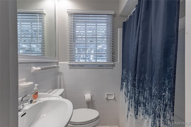 bathroom with a shower with curtain, toilet, tile walls, and sink