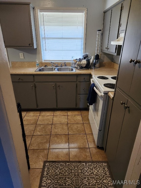 kitchen with gray cabinetry, ventilation hood, sink, light tile patterned floors, and white range with electric stovetop