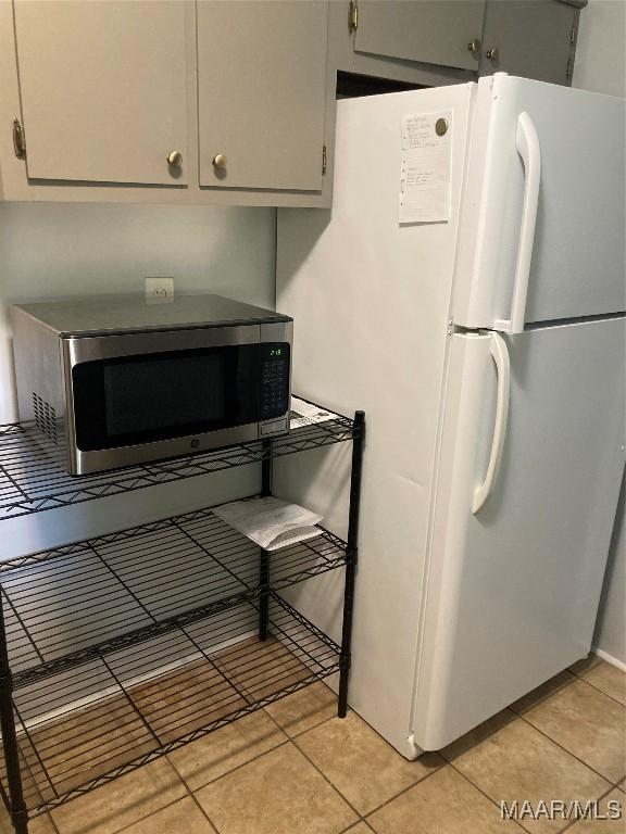 kitchen featuring gray cabinets, white fridge, and light tile patterned floors