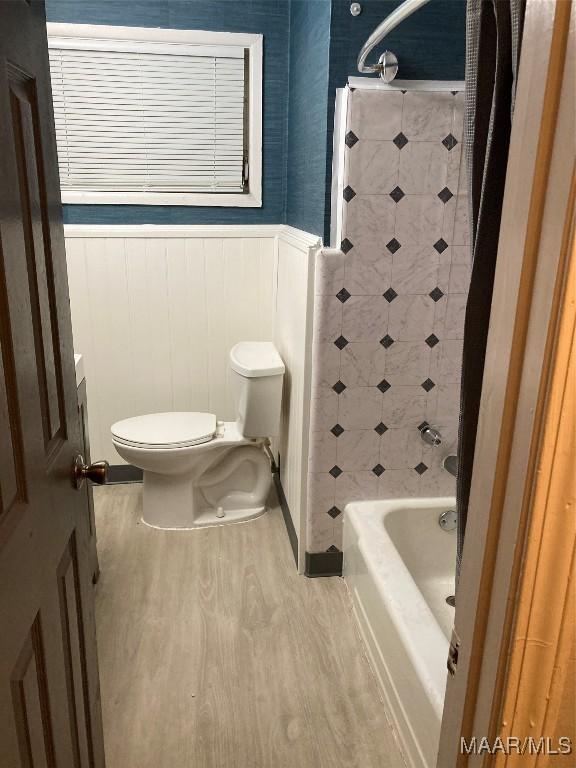 bathroom featuring wood-type flooring,  shower combination, and toilet