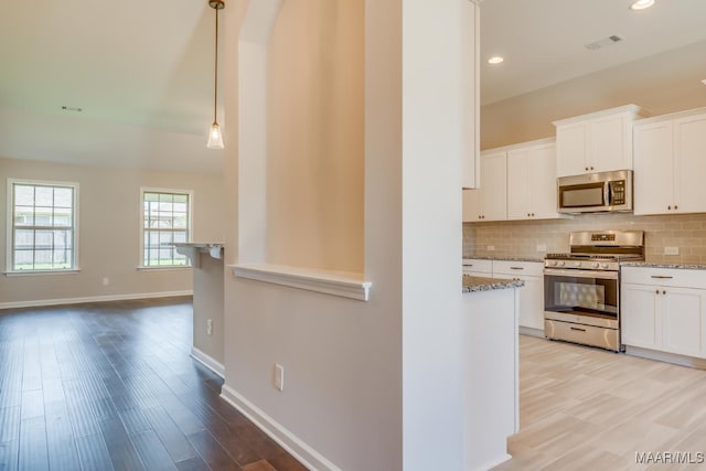 kitchen with visible vents, decorative backsplash, light stone counters, stainless steel appliances, and white cabinetry