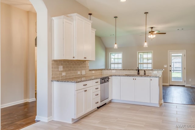 kitchen featuring tasteful backsplash, arched walkways, dishwasher, a peninsula, and a sink