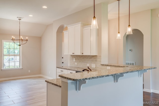 kitchen featuring white cabinetry, light stone countertops, tasteful backsplash, and a breakfast bar area