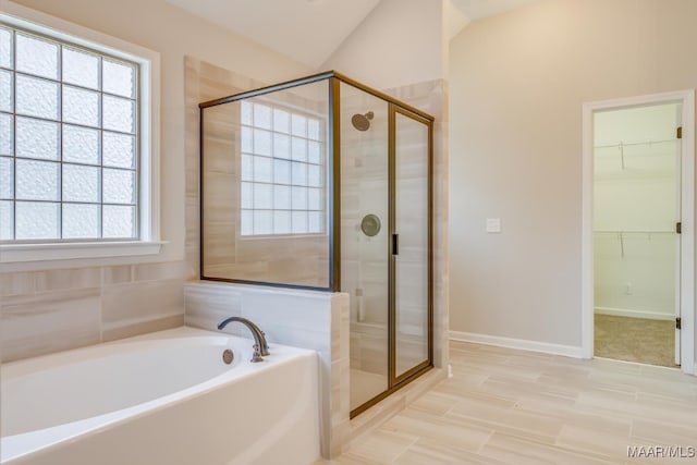 full bathroom with lofted ceiling, a garden tub, baseboards, a stall shower, and a walk in closet