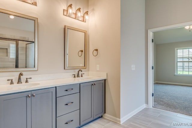 full bath featuring double vanity, a sink, and baseboards