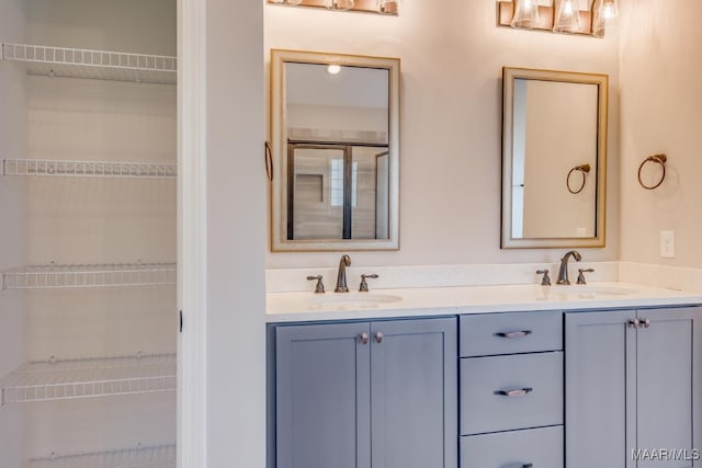 full bath featuring double vanity, a walk in closet, and a sink