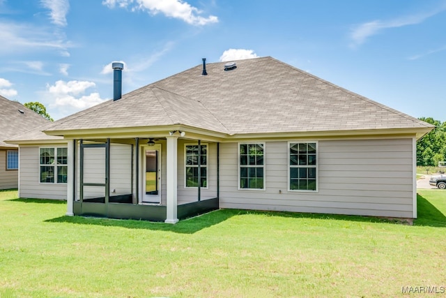 rear view of house with a yard, a shingled roof, and a sunroom