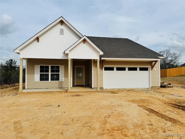 view of front facade featuring a porch, fence, roof with shingles, concrete driveway, and an attached garage