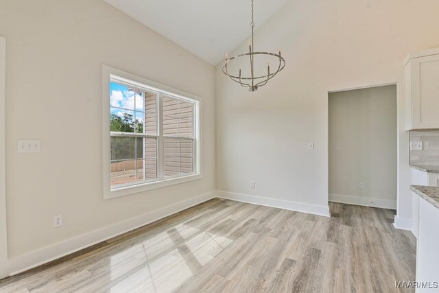 96 Madix Dr, Eclectic, AL 36024 - unfurnished dining area with light wood finished floors, a notable chandelier, high vaulted ceiling, and baseboards