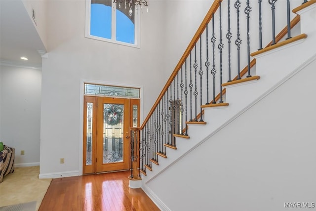 foyer featuring a high ceiling, hardwood / wood-style flooring, crown molding, and a healthy amount of sunlight