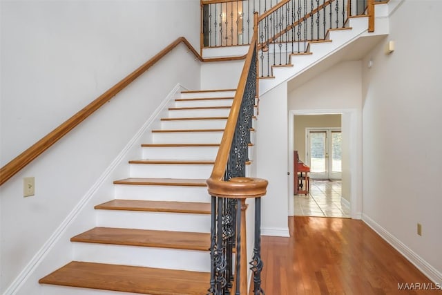 stairway featuring wood-type flooring and a high ceiling