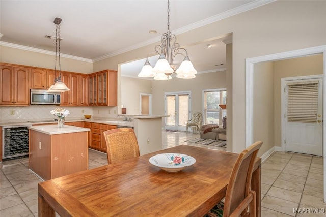 tiled dining space featuring wine cooler, crown molding, sink, and a chandelier