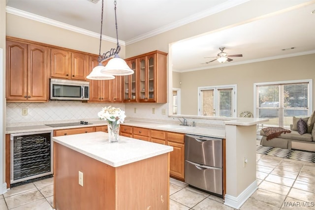 kitchen with appliances with stainless steel finishes, a center island, beverage cooler, and pendant lighting