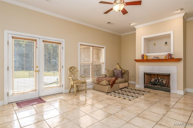 sitting room with a tiled fireplace, a wealth of natural light, and ornamental molding