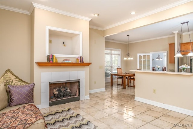 living room with a tile fireplace, a chandelier, ornamental molding, and light tile patterned flooring