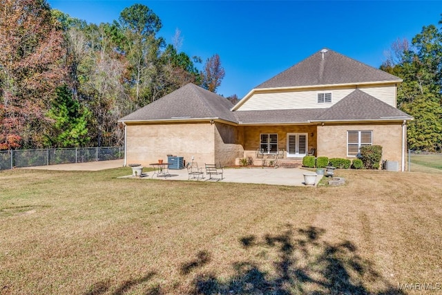 back of property with a lawn, central air condition unit, and a patio