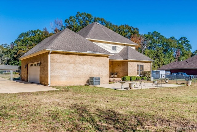 exterior space featuring a garage, a patio area, a yard, and central AC