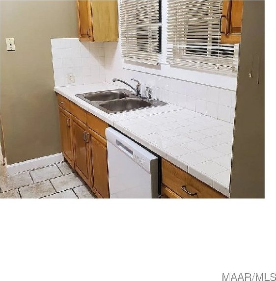 kitchen featuring dishwasher, sink, light tile patterned floors, tasteful backsplash, and tile counters