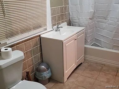 bathroom with tile patterned floors, vanity, toilet, and tile walls