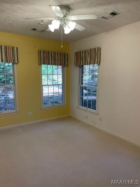 carpeted spare room with ceiling fan and a textured ceiling