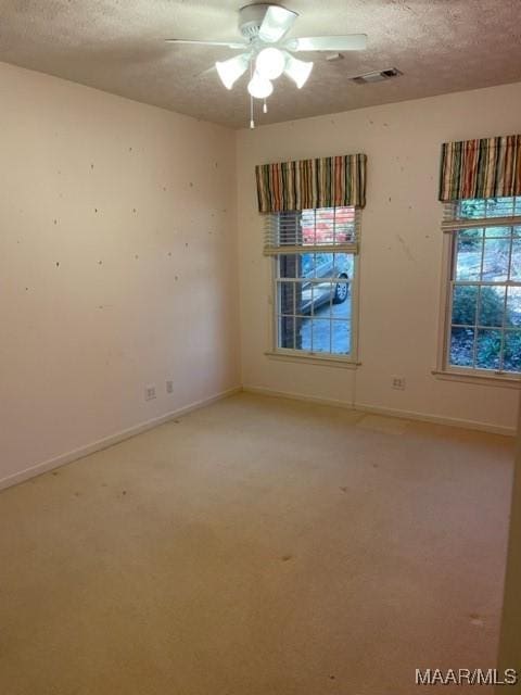 carpeted spare room with a wealth of natural light, ceiling fan, and a textured ceiling