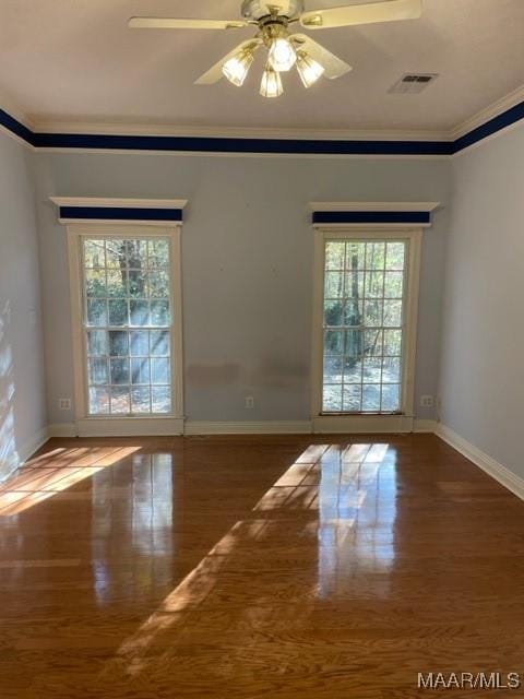 empty room with hardwood / wood-style floors, a wealth of natural light, and ornamental molding