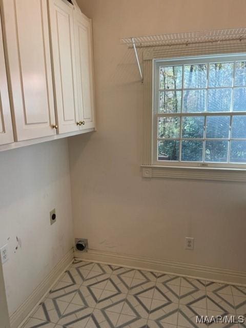 clothes washing area featuring hookup for an electric dryer, light tile patterned flooring, and cabinets