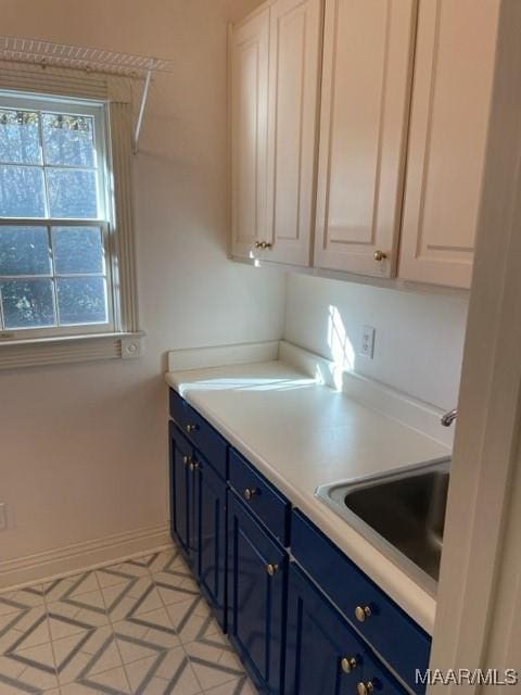 kitchen featuring white cabinets, sink, blue cabinets, and light tile patterned flooring