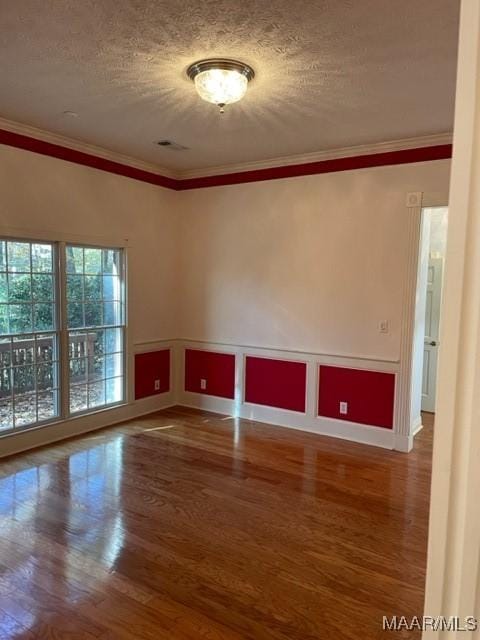 empty room featuring hardwood / wood-style floors, a textured ceiling, and crown molding