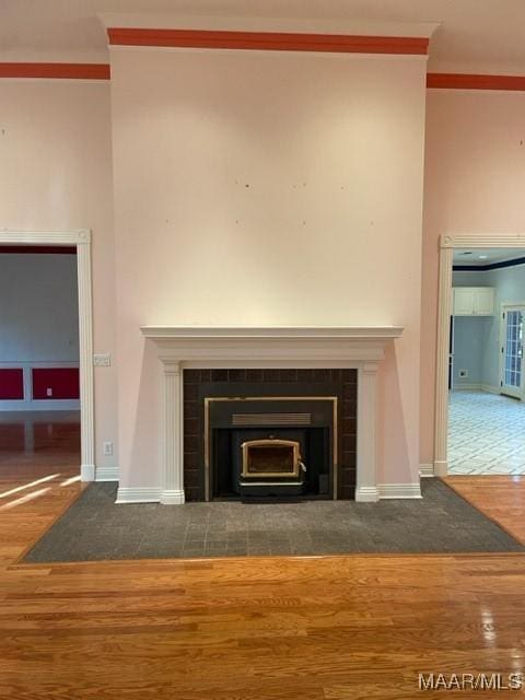 interior details featuring a tiled fireplace, crown molding, and hardwood / wood-style flooring