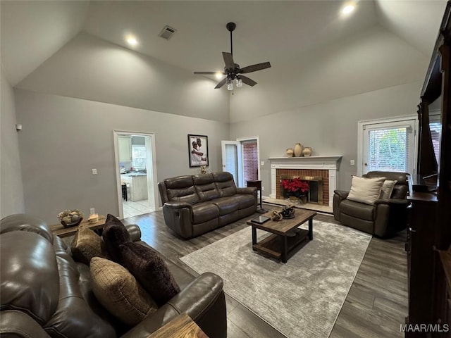 living room featuring lofted ceiling, a fireplace, ceiling fan, and dark hardwood / wood-style floors