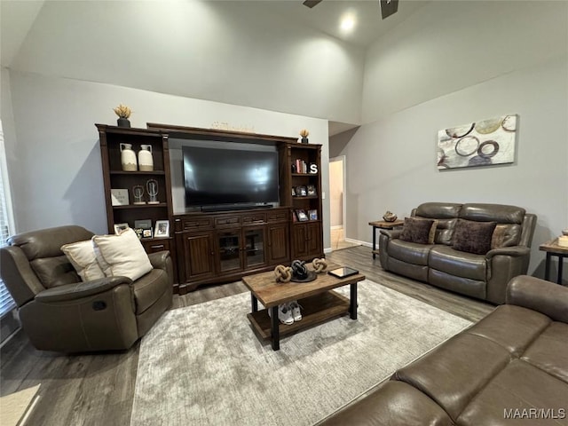 living room with ceiling fan, wood-type flooring, and vaulted ceiling