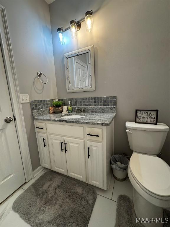 bathroom with toilet, vanity, and tile patterned floors