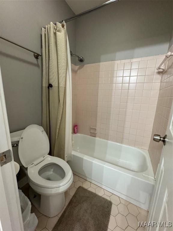 bathroom featuring tile patterned floors, shower / bath combination with curtain, and toilet