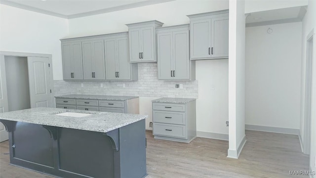 kitchen with a kitchen bar, backsplash, a center island, and light wood-type flooring