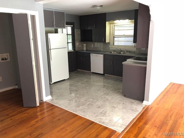 kitchen featuring tasteful backsplash, sink, light hardwood / wood-style floors, and white appliances