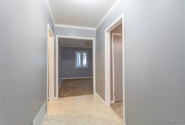 corridor with light colored carpet, ornamental molding, and a textured ceiling