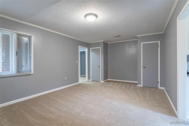 unfurnished room featuring light colored carpet, ornamental molding, and a textured ceiling