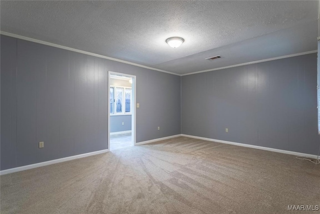 empty room featuring carpet, a textured ceiling, and ornamental molding