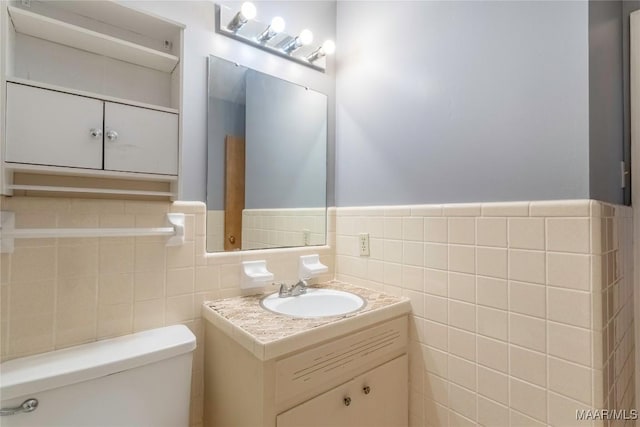 bathroom featuring vanity, toilet, and tile walls