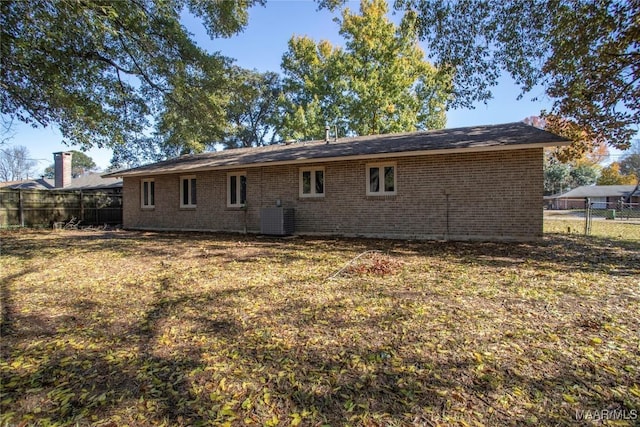 rear view of house featuring central AC unit and a lawn