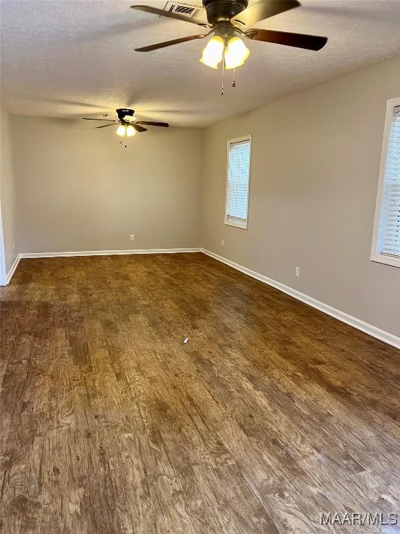 unfurnished room with a textured ceiling and dark wood-type flooring