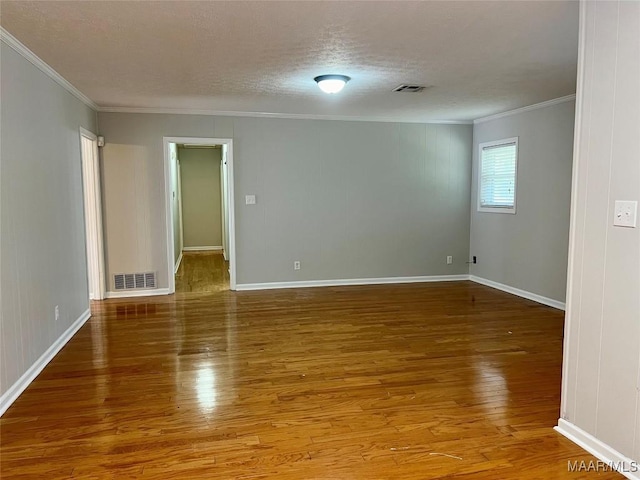 empty room featuring hardwood / wood-style floors, a textured ceiling, and ornamental molding