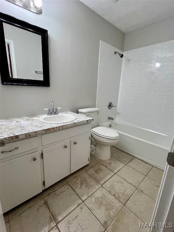 full bathroom featuring vanity, tile patterned flooring, tiled shower / bath combo, toilet, and a textured ceiling