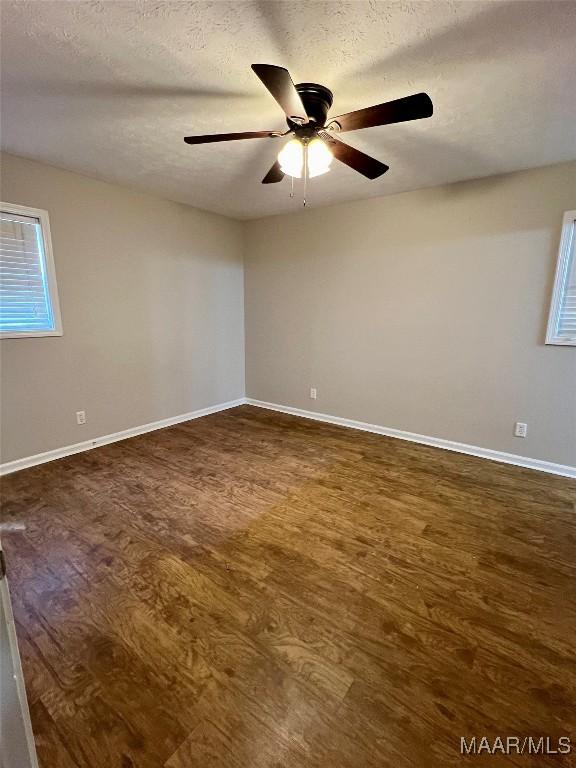 spare room featuring a textured ceiling, ceiling fan, and dark wood-type flooring